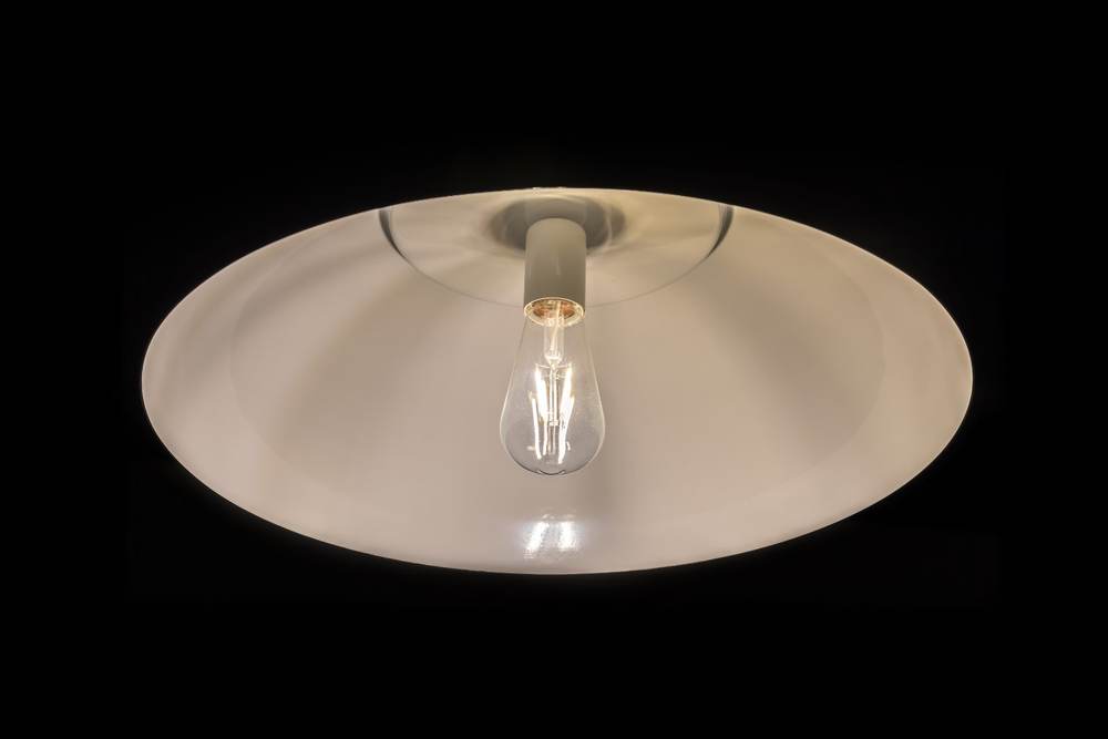 A single lit incandescent bulb hanging against a black background, interrogation-room style